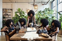 a group of afro haired women sitting around a table