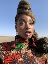 a woman in a colorful dress is standing in the desert